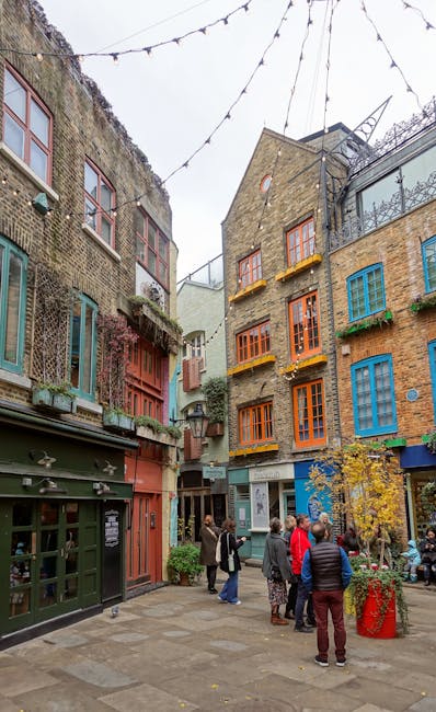 The image shows a charming urban scene in Neal Street Covent Garden with colorful, multi-story buildings featuring vibrant window frames in shades of blue, orange, and green. String lights are suspend