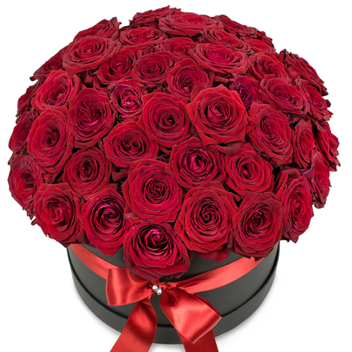An opulent bouquet of rich red roses, professionally arranged in a modern matte black hat box, is the focal point of this image. Each stem, sourced fresh from the renowned Covent Garden Flower Market, contributes a premium bloom with velvety, tightly furled petals at their center and softly opening tips at the edges. Together, these dozens of crimson roses are densely gathered to form a plush, perfectly rounded dome that spills elegantly beyond the rim. A radiant, wide red satin ribbon encircles the hatbox, tied in an immaculate bow at the front, its sheen highlighted by a small, sparkling crystal detail that adds gentle glamour. The vivid red and the darkly contemporary black stand in sophisticated contrast, evoking both classic romance and the vibrant creative scene found in Covent Garden's historic piazza. The arrangement is staged against a brilliant white background, emphasizing every luxurious facet and the fresh, seductive appeal of the blooms. This bouquet is ideal for marking a milestone romance-be it an anniversary dinner above Floral Street or a grand declaration in Leicester Square-capturing the opulence and heartfelt artistry local to central London, and reinforcing the boutique's reputation for premium flower delivery and unforgettable gestures.