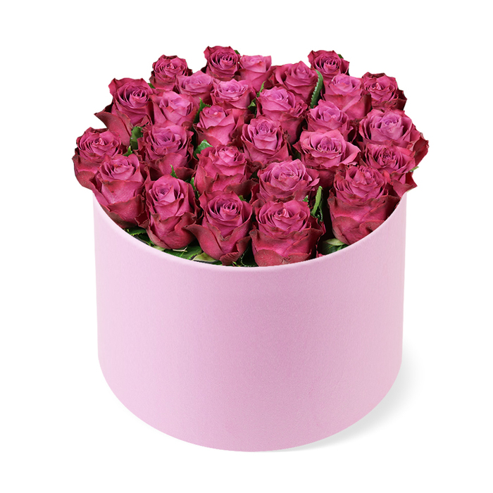 A sophisticated round hat box of roses is captured in a clean studio-style image, evoking the refined atmosphere of Covent Garden's boutique shops and hidden courtyards. The hat box is a soft, pastel blush pink with a delicately textured, matte surface that suggests a velvet-touch finish. It stands upright on a pure white background, casting a faint, subtle shadow that anchors it in space without distracting from its elegance. Overflowing from the top is a meticulously crafted dome of roses in a deep fuchsia-magenta hue, so densely clustered that they create a continuous, undulating surface of petals. Each rose appears freshly cut, with tightly wound centres that lighten to a gentle rosy pink, then gradually transition into saturated, berry-like tones at the outermost petals. This natural gradient of colour within each bloom adds dimension, making the arrangement appear almost three-dimensional even in a flat photograph. The petals are soft and velvety, their edges gently curled and unblemished, suggesting the careful handling of an experienced florist. Only the slightest hints of dark green foliage are visible in the shadows between blooms, offering a whisper of contrast that subtly deepens the overall palette. The composition is calm and balanced, with even lighting that emphasises the bouquet's rich colour and luxurious texture. It feels like the kind of premium floral gift chosen for a proposal dinner in one of Covent Garden's intimate restaurants, or delivered to a townhouse by the market as a lavish Valentine's Day surprise. The arrangement conveys romance, celebration, and a polished sense of luxury, ideal as a modern alternative to a traditional bouquet.